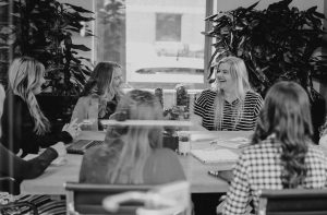 Marketing team sat round a table having a meeting and smiling