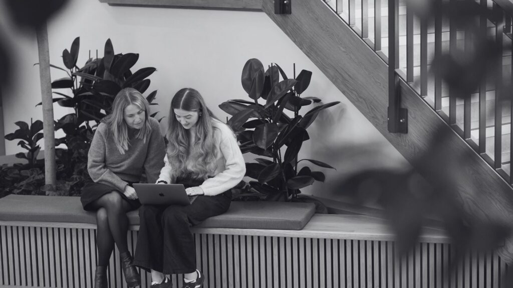 Two marketing colleagues sat together, looking at a laptop.