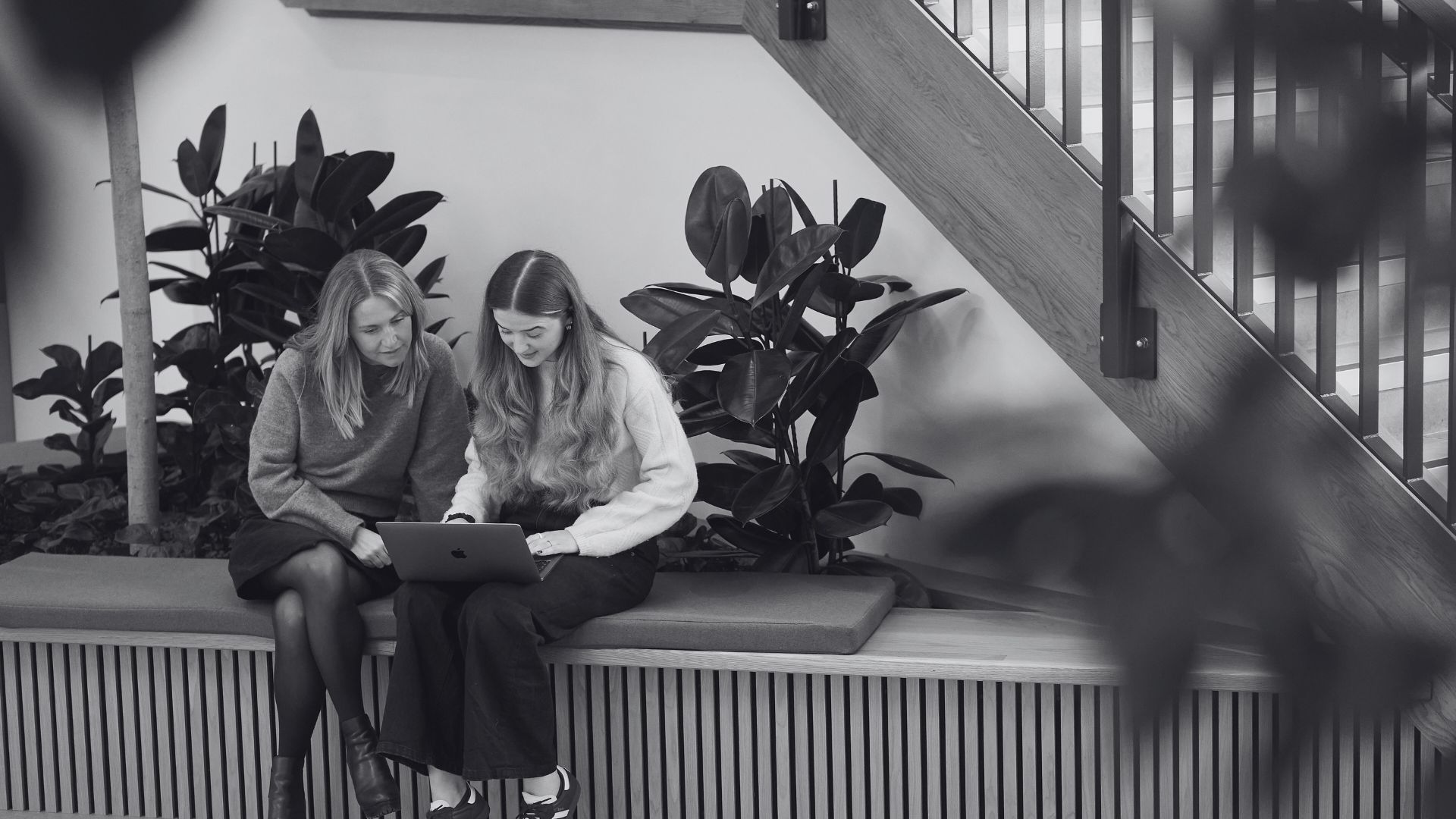 Two marketing colleagues sat together, looking at a laptop.