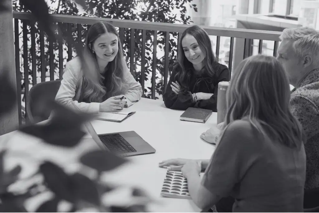 Marketing team sat around a table looking at a laptop together.