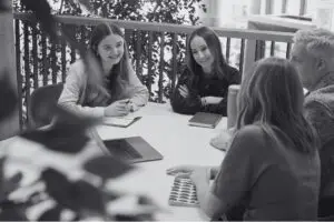 Marketing team sat around a table looking at a laptop together.